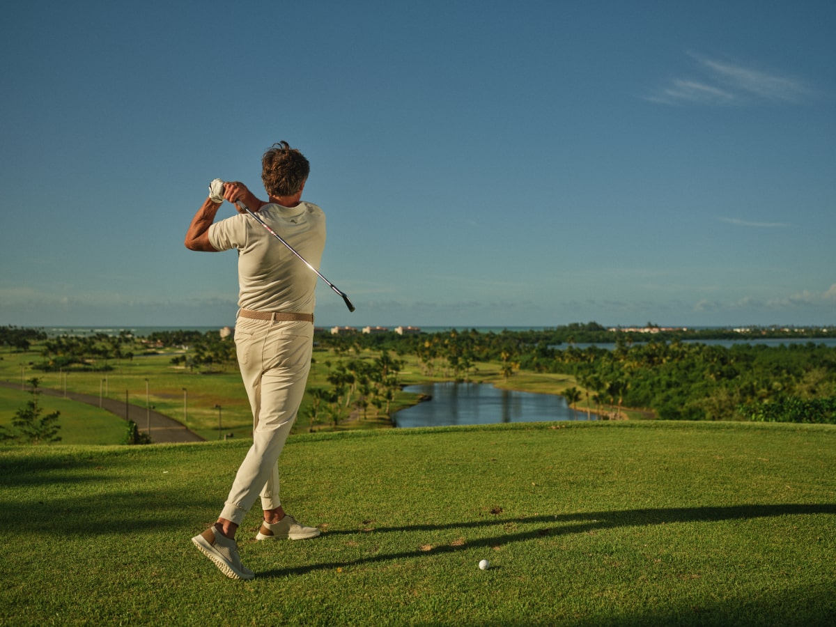 A golfer takes a mid-swing at Grand Reserve's world-class golf course, with a breathtaking backdrop of the resort's lush landscapes and tranquil waters