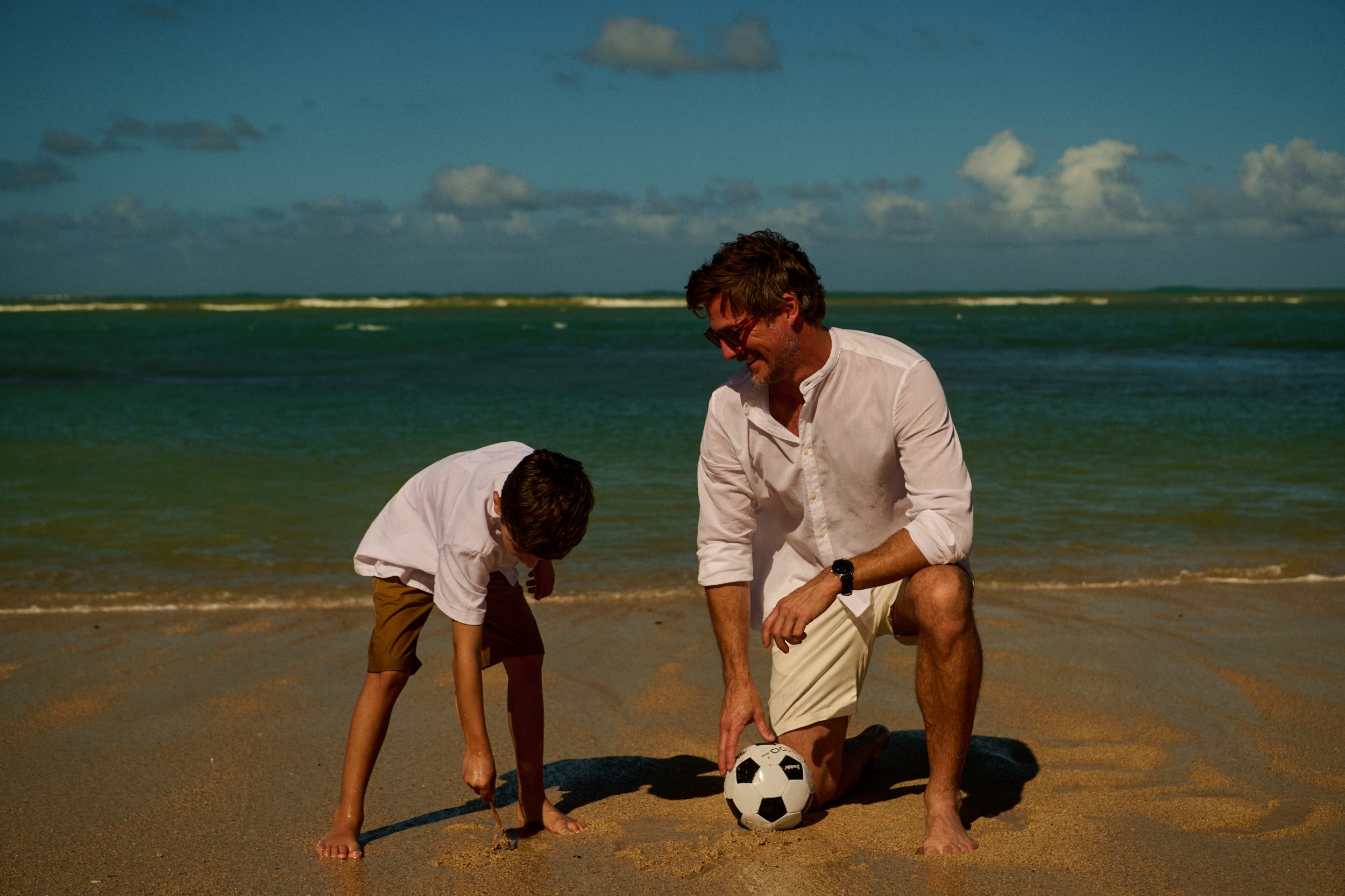 A father and son share a heartwarming moment on Grand Reserve's idyllic beach, symbolizing the cherished memories created at this luxurious getaway