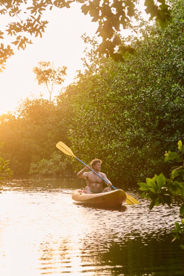 An adventurer at Grand Reserve kayaks through serene waters, surrounded by the lush mangroves of Puerto Rico, offering a blend of tranquility and exploration