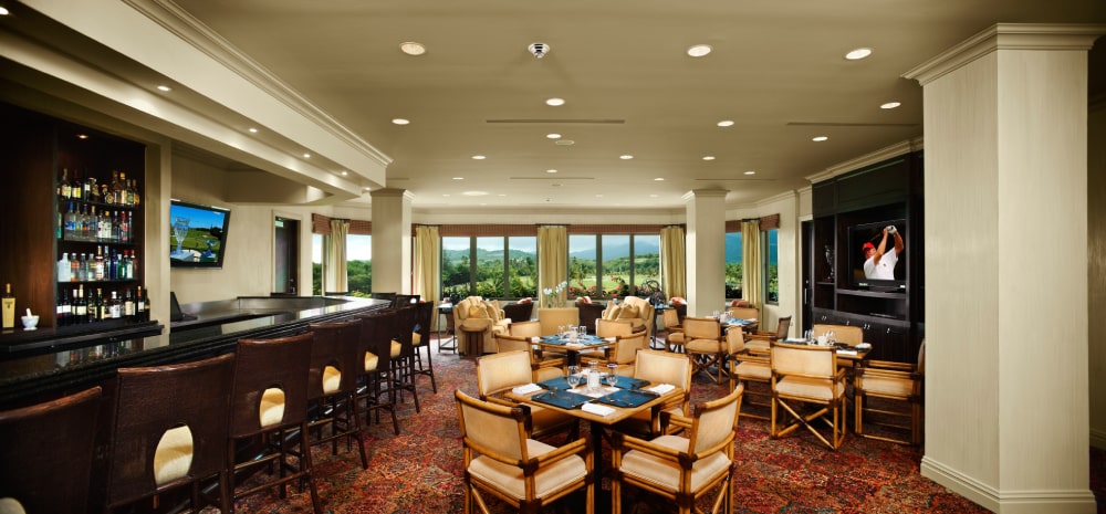 Inside Grand Reserve's Golf Club, a sophisticated room with a grand bar, elegant seating, and a view of the golf course exudes luxury