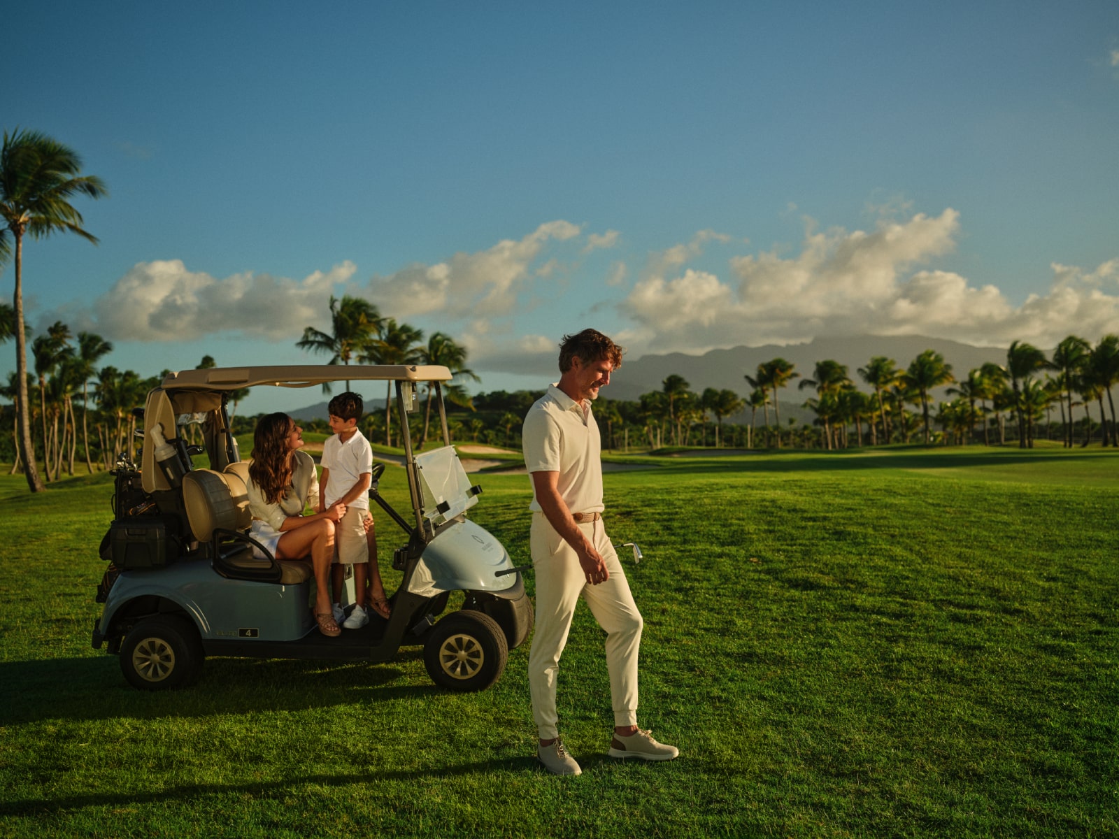 A family enjoys a leisurely golf cart ride along the lush fairways of Grand Reserve, capturing the joy of shared experiences in a luxurious setting